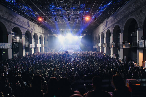 Audience and illuminated stage inside a vaulted hall in Innsbruck
