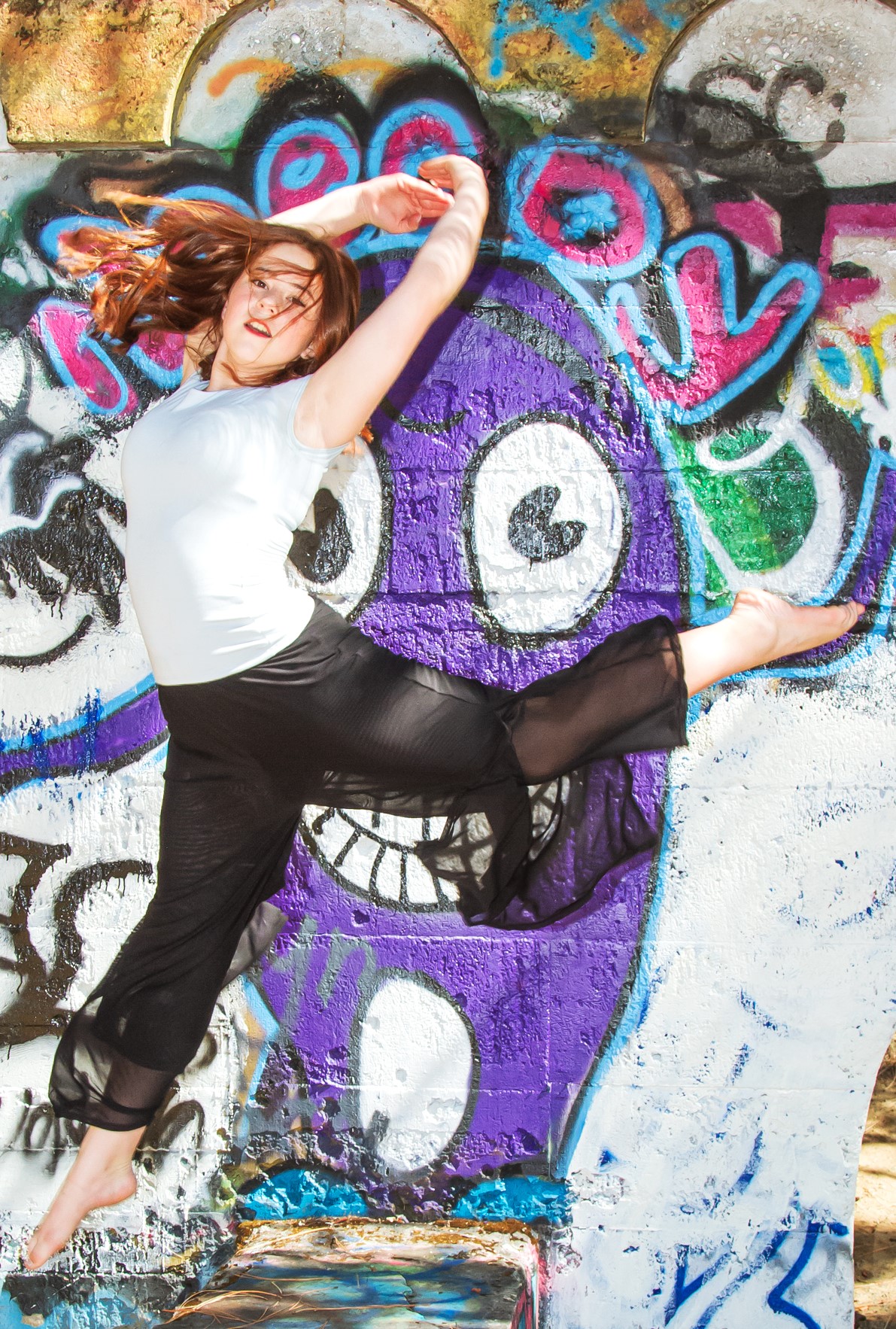 Lydia jumping in front of a colorful graffiti wall