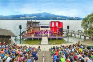 Lakeside performance stage and outdoor audience in Seeham
