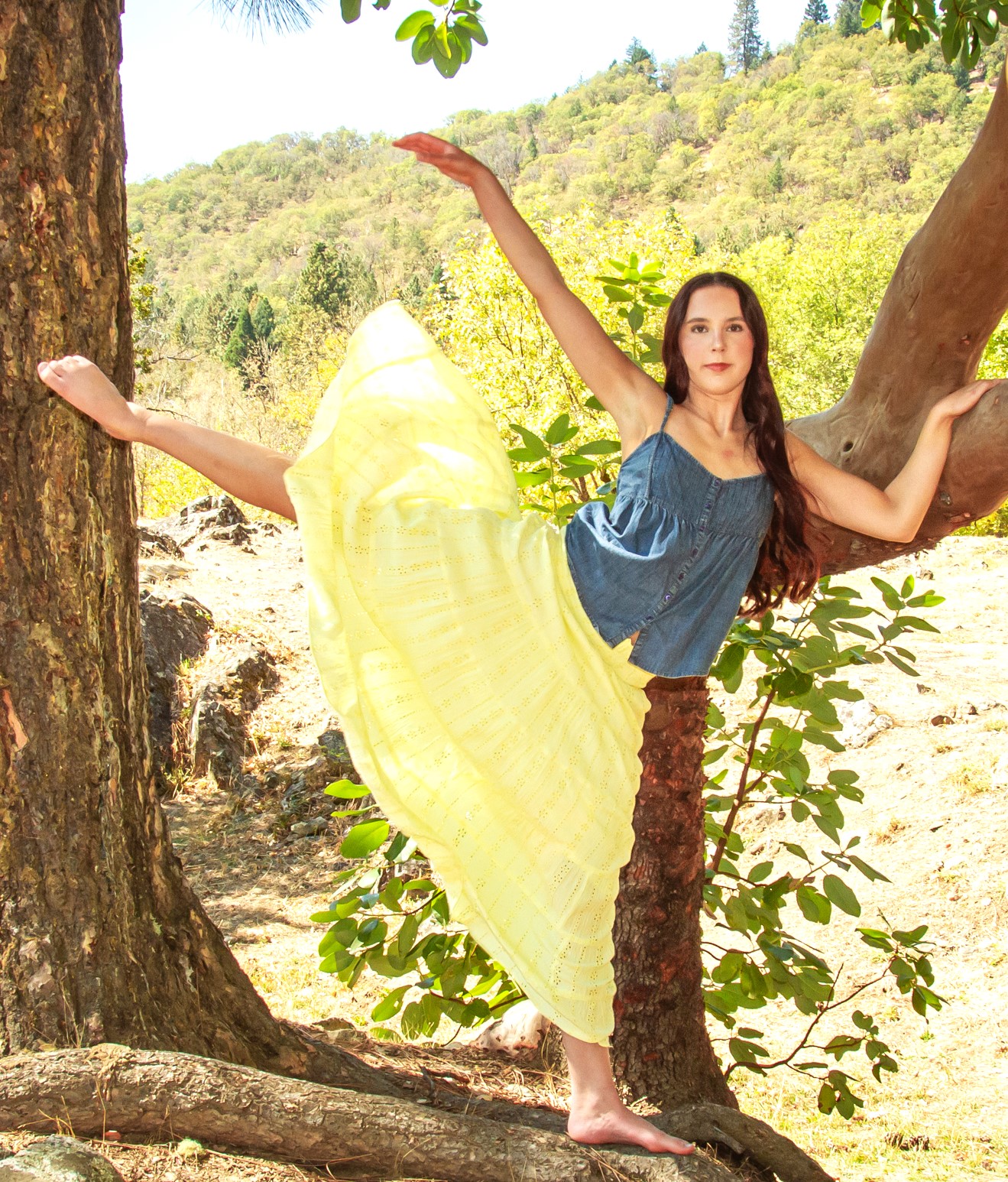 Danielle extending her leg beside a tree outdoors